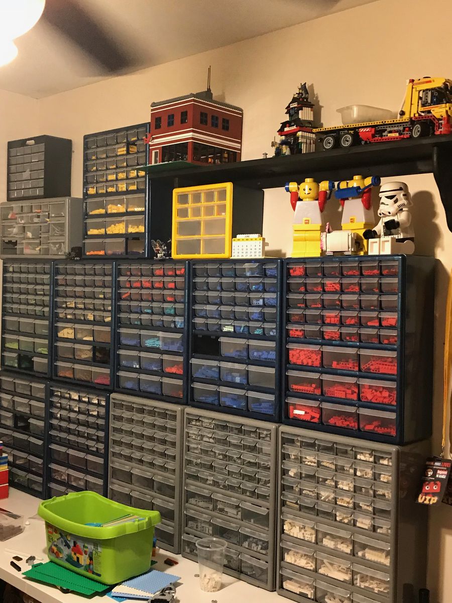 A wall of organized LEGO parts storage with built MOCs on top